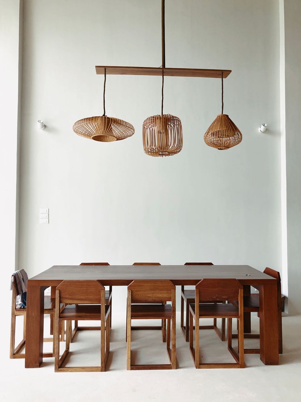 Tre lampade a sospensione in terracotta smaltata avorio sopra un lungo tavolo di rovere in una cucina con travi e pavimento in cotto